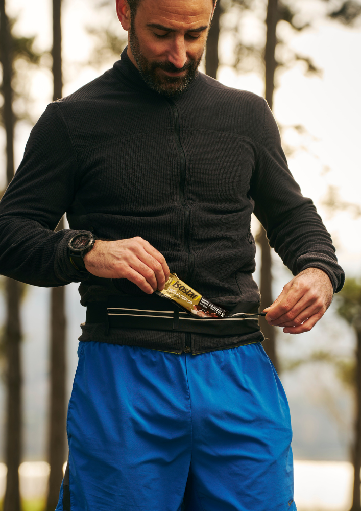 Athlete placing an Isostar energy bar in a waist-belt pocket
