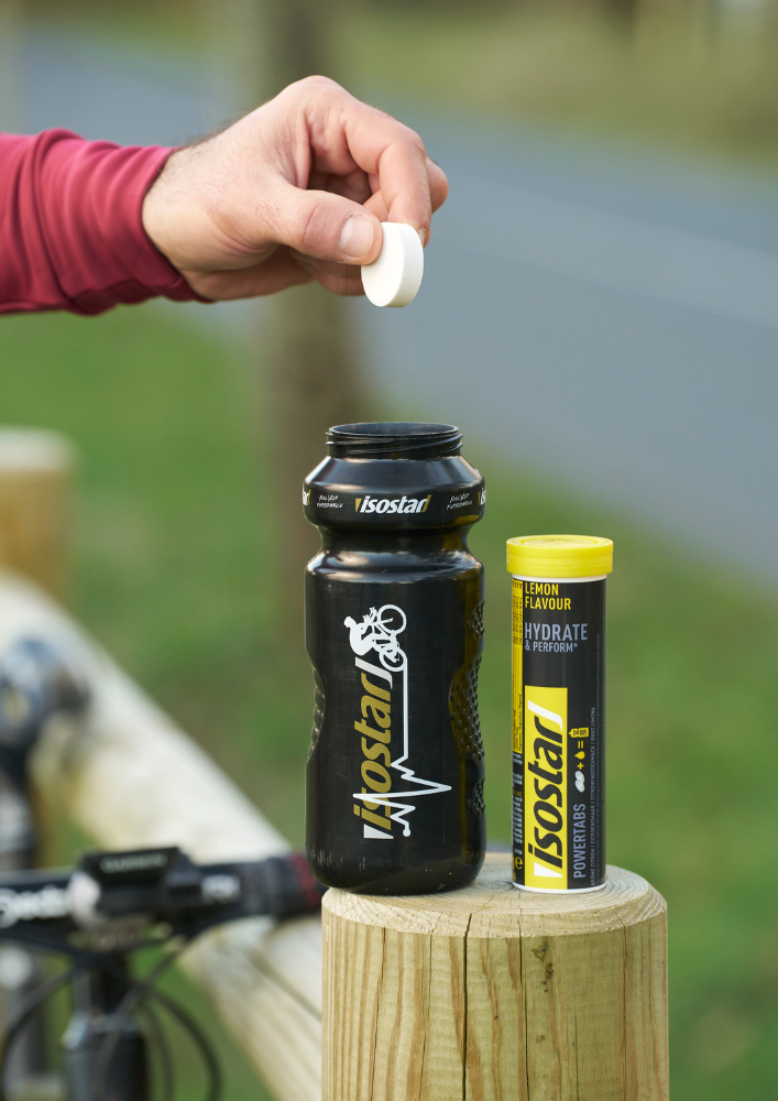 Adding an Isostar electrolyte tablet to a sports bottle